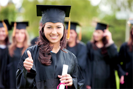 A photo of a girl wearing a graduation cap and gown, holding a diploma while smiling and giving a "thumbs up".